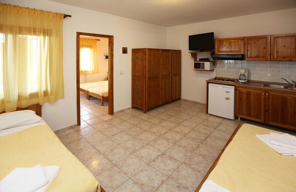 Une chambre d’hôtel compacte comprenant un lit, une petite kitchenette et une salle de bain visible à travers une porte ouverte.