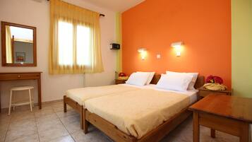 A room with two wooden beds, a desk, a chair, a mirror, and a window with curtains.