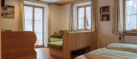 Una habitación de madera con una cama, una silla y una ventana con cortinas.