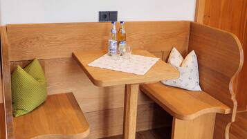A wooden bench with a table, two bottles, and glasses on a placemat.