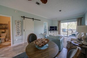 A living room with a sofa, a TV, and a dining area with a table and chairs.
