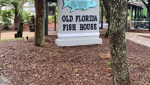 Schild des Old Florida Fish House, umgeben von Bäumen und einem überdachten Bereich.
