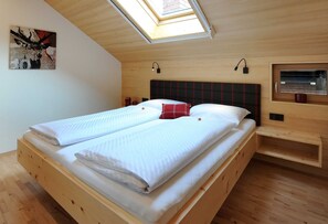 Quarto com cama de madeira, claraboia, cabeceira, mesa de cabeceira e janela.