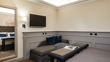 A modern hotel room with a large bed, a sofa bed, a flat-screen TV, and a bedside table.