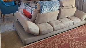 A living room with a beige sofa, a blue armchair, a television, a ceiling fan, and a large painting of a beach scene. - Relaxing country style home with spacious backyard in a quiet neighborhood. (Peoria)
