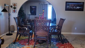 A dining area with a ceiling fan, a dining table with chairs, a colorful rug, and a large window with curtains. - Relaxing country style home with spacious backyard in a quiet neighborhood. (Peoria)