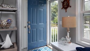 A room with a blue door, a ship's wheel decoration, a lamp, and a white swan sculpture.