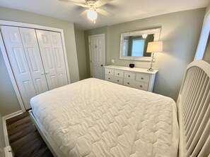 Un dormitorio con cama, cómoda, espejo y ventilador de techo.