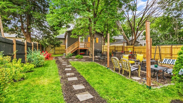 A backyard with a wooden deck, a stone pathway, and outdoor furniture.