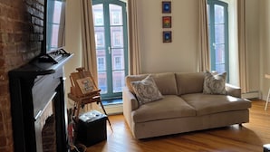 Ein Wohnzimmer mit Kamin, einer Couch und einem Gemälde auf Staffelei.