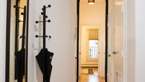Ein Flur mit Holzboden, einem Kleiderständer und einem Spiegel an der linken Wand.