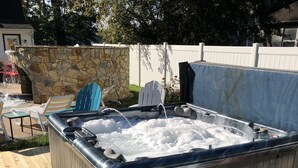 Ein Whirlpool vor einer Steinsäule, mit Holzterrasse und blauen Stühlen.