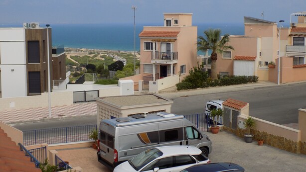 Un quartier résidentiel offrant une vue sur la mer, avec des bâtiments modernes, un fourgon stationné et une voiture.