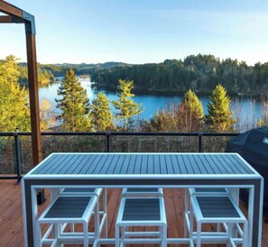 A deck with a table and chairs overlooking a lake surrounded by trees. - Tenmile Lakeview Hideaway (Lakeside)