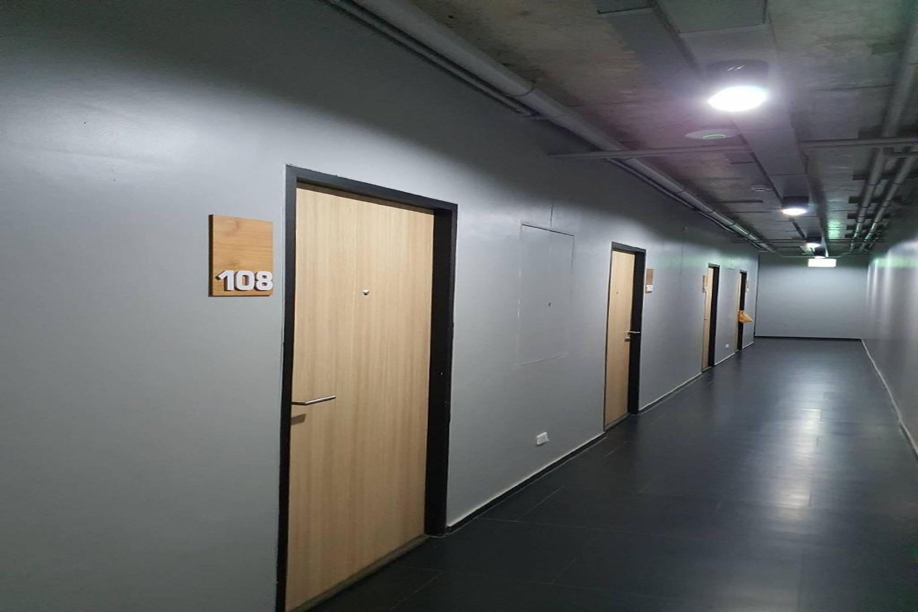 Pasillo con puertas numeradas 108, 109 y 110, que dan a habitaciones individuales.