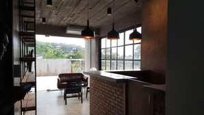 A modern interior with a bar area, seating, and large windows offering a view. - Be Live Residence (Thep Krasattri)