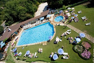 Una piscina techada, una piscina al aire libre, sombrillas