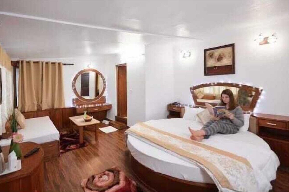 A bedroom with a large bed, a bedside table, a mirror, a dresser, and a desk with a chair.
