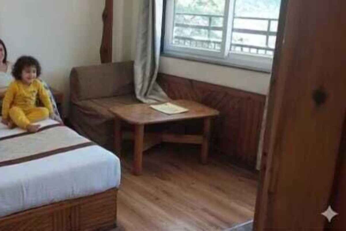 A room with a bed, a small table, and a window.