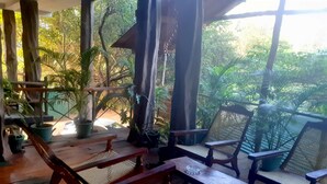 A covered outdoor seating area with wooden furniture and potted plants. - Sigiri Heritage Villa (Sigiriya)