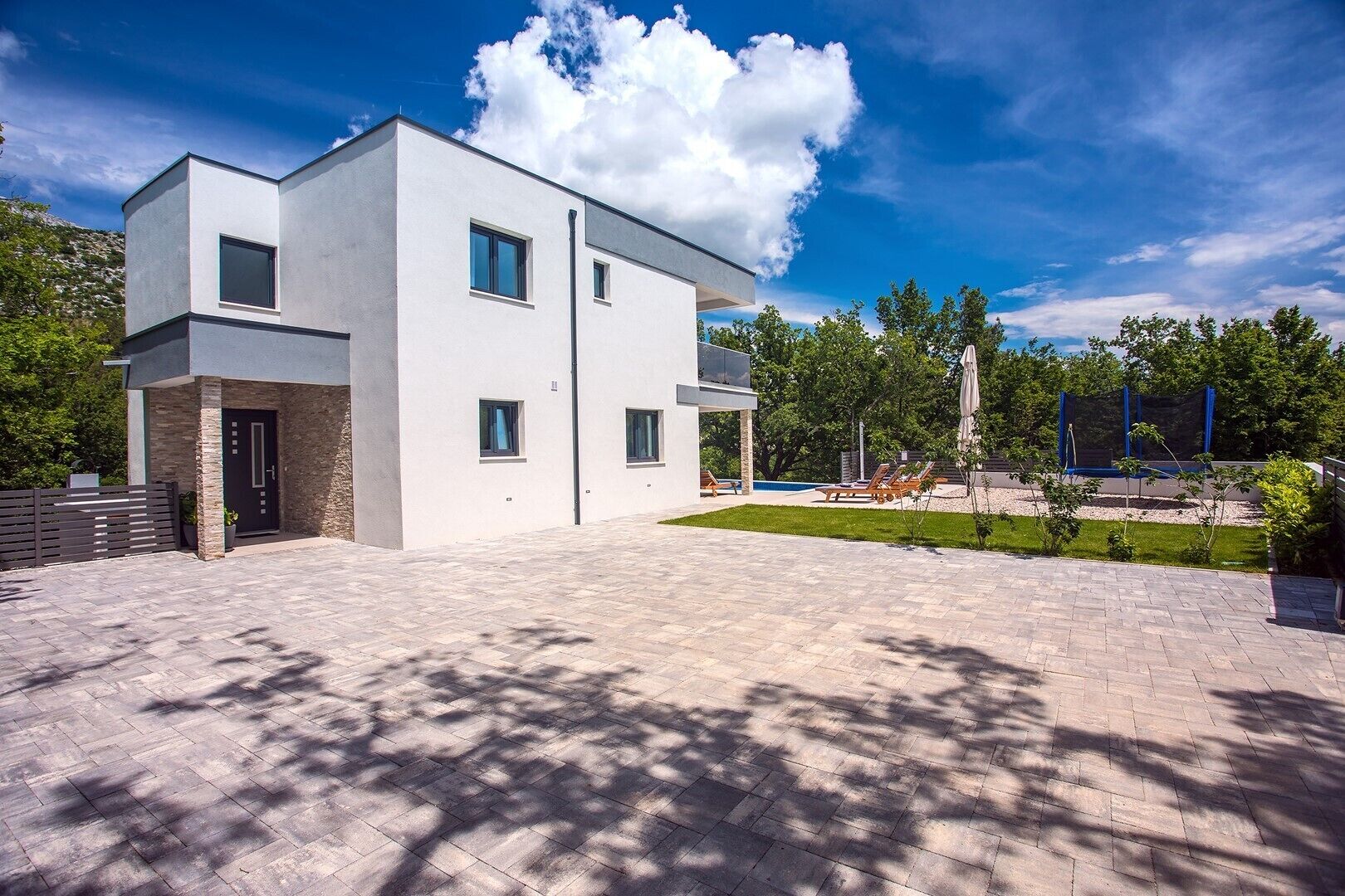 A modern two-story house with a paved driveway and a small lawn area.