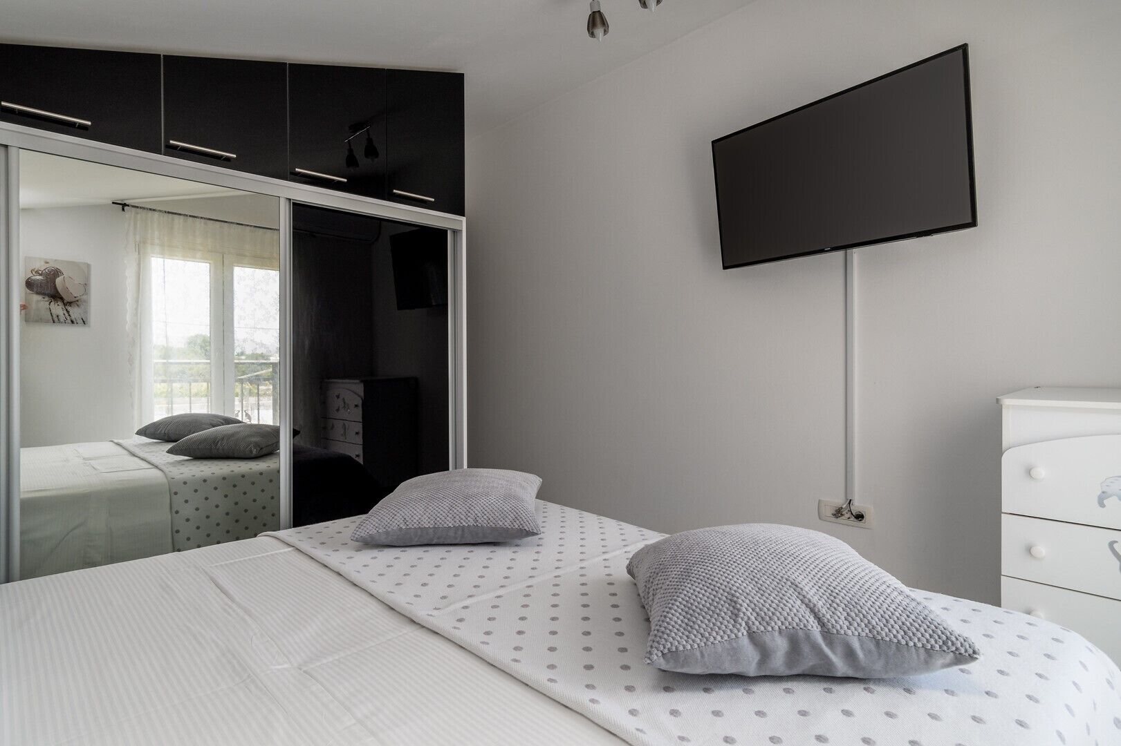 A bedroom with a bed, a wardrobe, a TV, and a dresser.