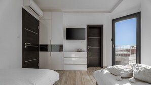 Ein modernes Schlafzimmer mit zwei Betten, einem Fernseher und einem Balkon.