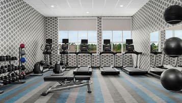 A gym with treadmills, elliptical machines, and free weights.