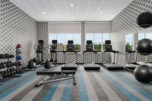 Une salle de sport équipée de tapis de course, de vélos elliptiques et de poids libres.