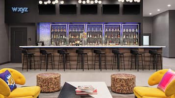 Un espace bar proposant différents types de sièges, un panneau lumineux au néon et une variété de bouteilles d’alcool.