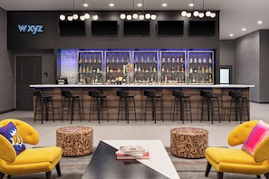 A bar area with multiple seating options, a neon sign, and a variety of liquor bottles.