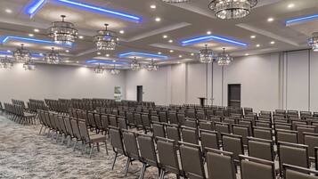 Une salle de conférence avec des rangées de chaises, des lustres et un sol recouvert de moquette.