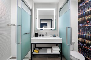 Un bagno moderno con cabina doccia in vetro, lavandino bianco e servizi igienici.