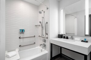 Un bagno moderno con vasca, doccia e lavabo con un ampio specchio.