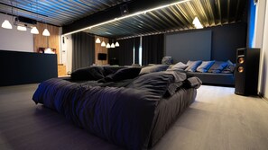 Een moderne slaapkamer met een groot bed, een bank en een audiosysteem.