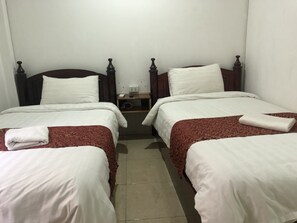 A hotel room with two single beds, each with a wooden headboard, white bedding, and a red patterned bedspread. There is a nightstand with a lamp and a phone between the beds. - Little Freedom Friendlys Place (Luang Prabang)