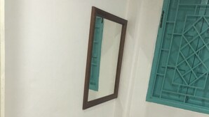 A corner room with a wooden bench, a mirror, and a window with a geometric pattern. - Little Freedom Friendlys Place (Luang Prabang)