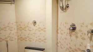 A small bathroom with a toilet, a sink, and a shower. - Hotel Imperial (Vasai)