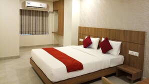 A hotel room with a large bed, wooden headboard, and a window with curtains. - Hotel Imperial (Vasai)