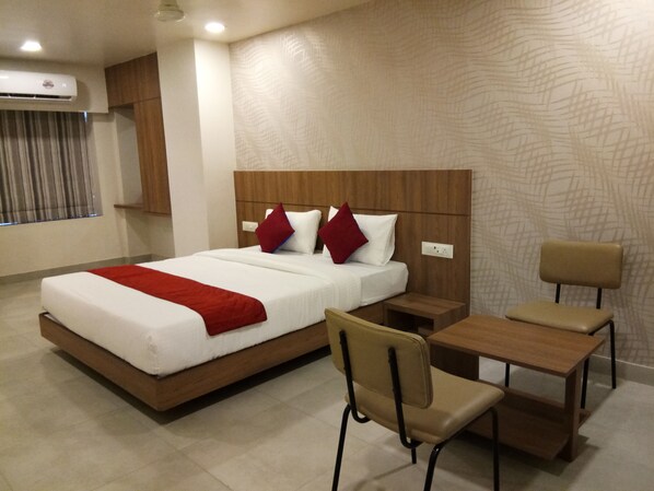 Una habitación de hotel con una cama grande, cabecera de madera, un escritorio y una silla.