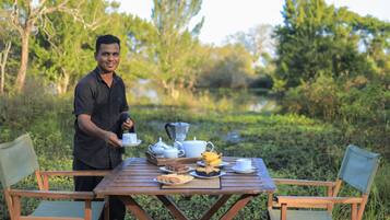 A wooden table set outdoors with a person serving food.