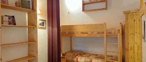 Una habitación con una litera, estantes de madera y un reloj en la pared.