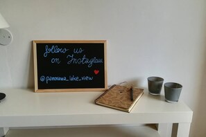 A blackboard with a message to follow on Instagram, a notebook, and two metal cups on a white table.
