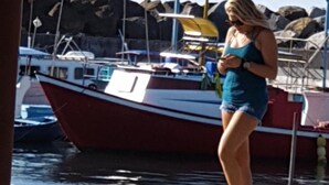 Une personne se tient sur un quai, avec des bateaux en arrière-plan.