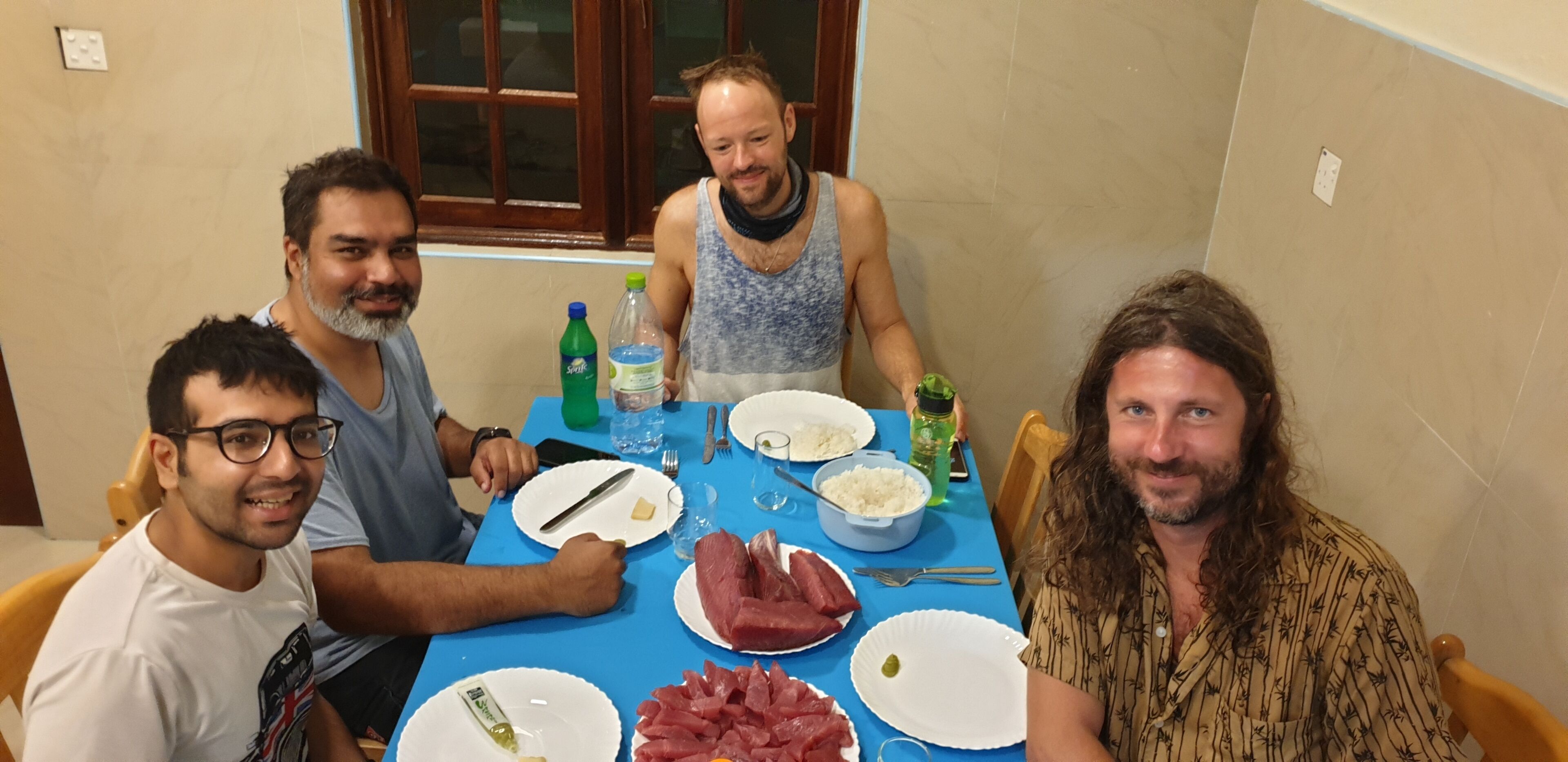 Un gruppo di persone sedute attorno a un tavolo con cibo e bevande.