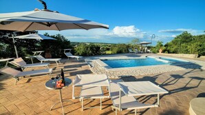 Uma área de piscina com espreguiçadeiras e guarda-sóis.