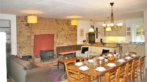 Una sala de estar acogedora con chimenea, un comedor listo para una comida y una cocina al fondo.