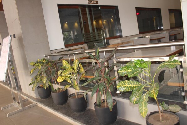A reception area with potted plants, a staircase, and a sign reading "A.C. HALL". - Hotel Satkar Chhatral (Kalol)