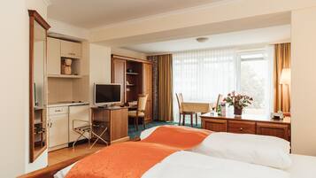 Ein Hotelzimmer mit zwei Betten, einem Schreibtisch mit Fernseher, einer Küchenzeile und Blick ins Freie.