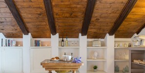 A kitchen with a wooden ceiling, white cabinets, and a table with a vase of flowers. - Le Cupole - Suite Panoramica by Wonderful Italy (Ostuni)